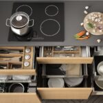 Opened wooden kitchen drawer with accessories inside, solution for kitchen storage and organizing, cooking, modern interior design